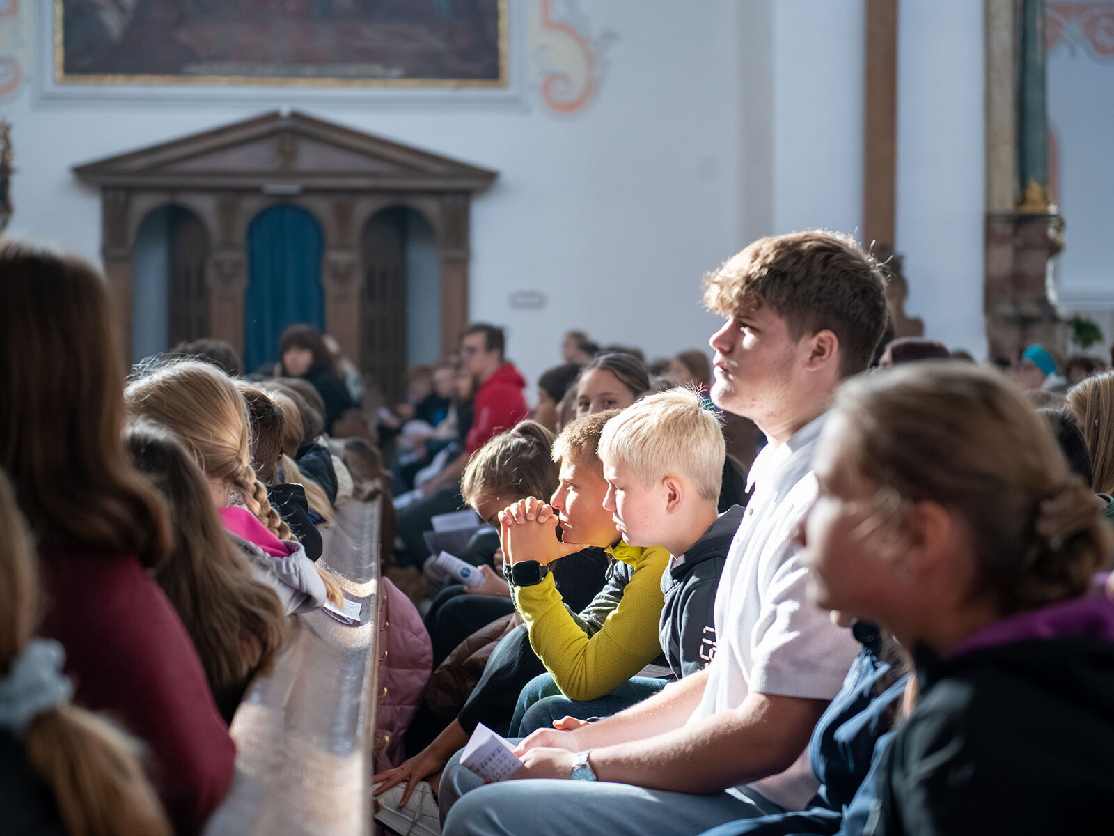 Schülerinnen und Schüler in den Kirchenbänken der Basilika St. Peter in Dillingen