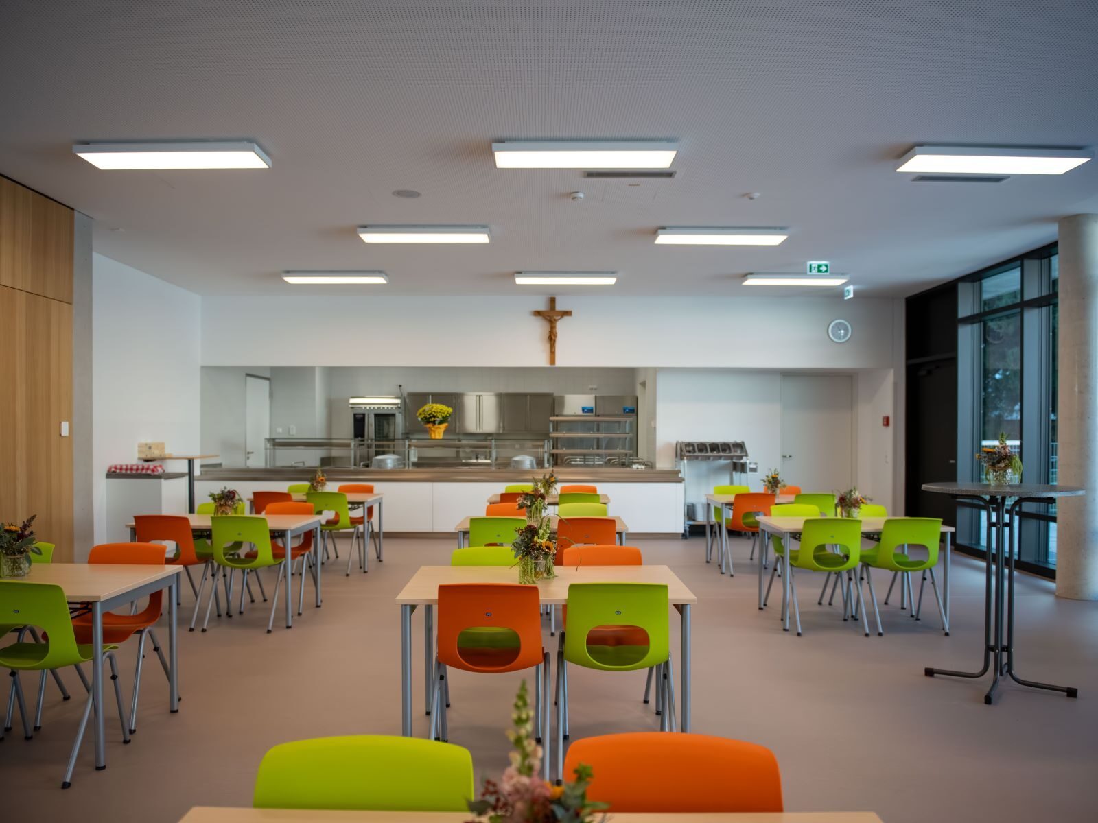 Neue Mensa mit grün-orangen Stühlen und Kruzifix im Bona-Campus Dillingen
