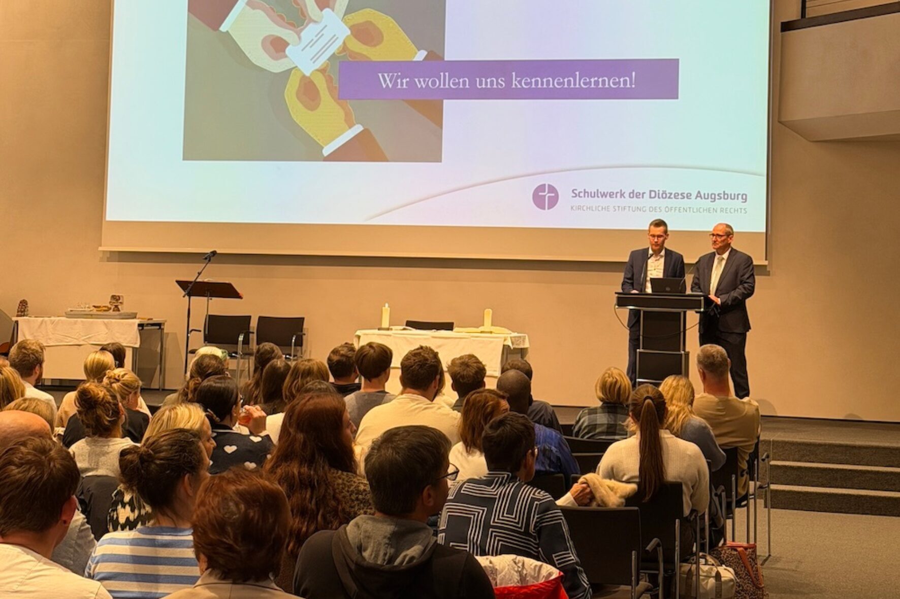 Neue Lehrkräfte beim Einführungstag vor der Leinwand im Haus St. Ulrich, Schulwerk Augsburg