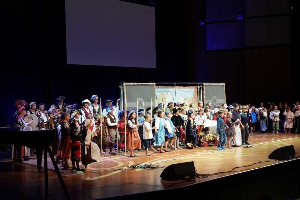 Großes Ensemble im Mini-Musical Frundsberg vor Stadtkulisse, Best of Schulwerk