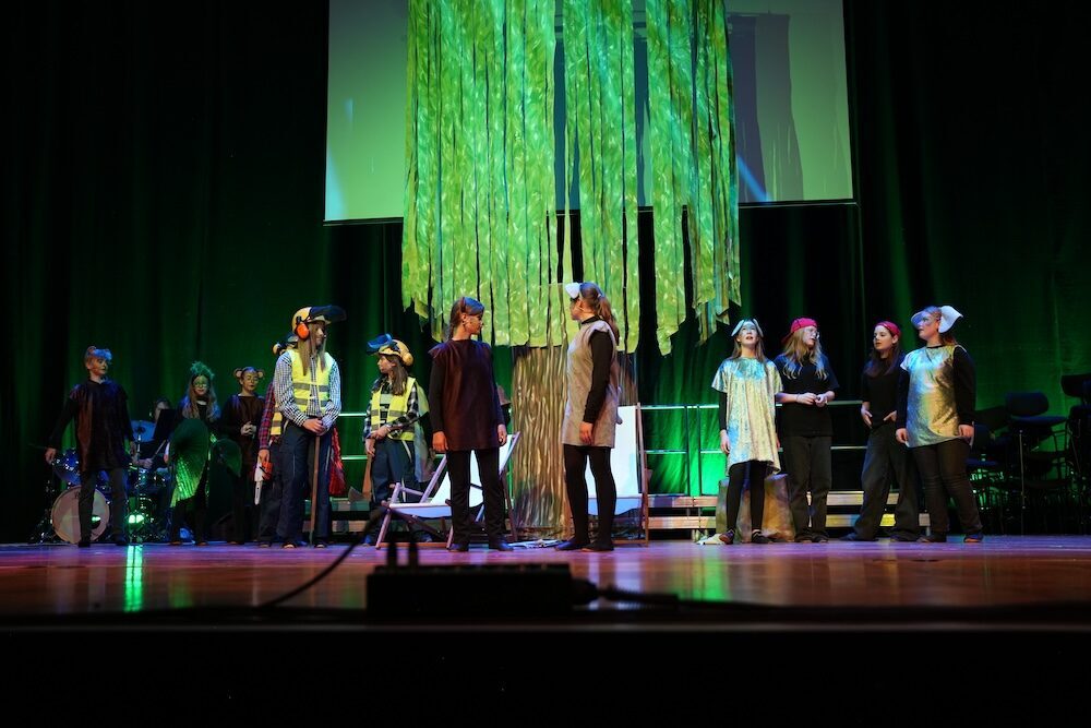 Musicalszene um den Baum mit Helmen und Tuniken, Urwald-Musical Best of Schulwerk